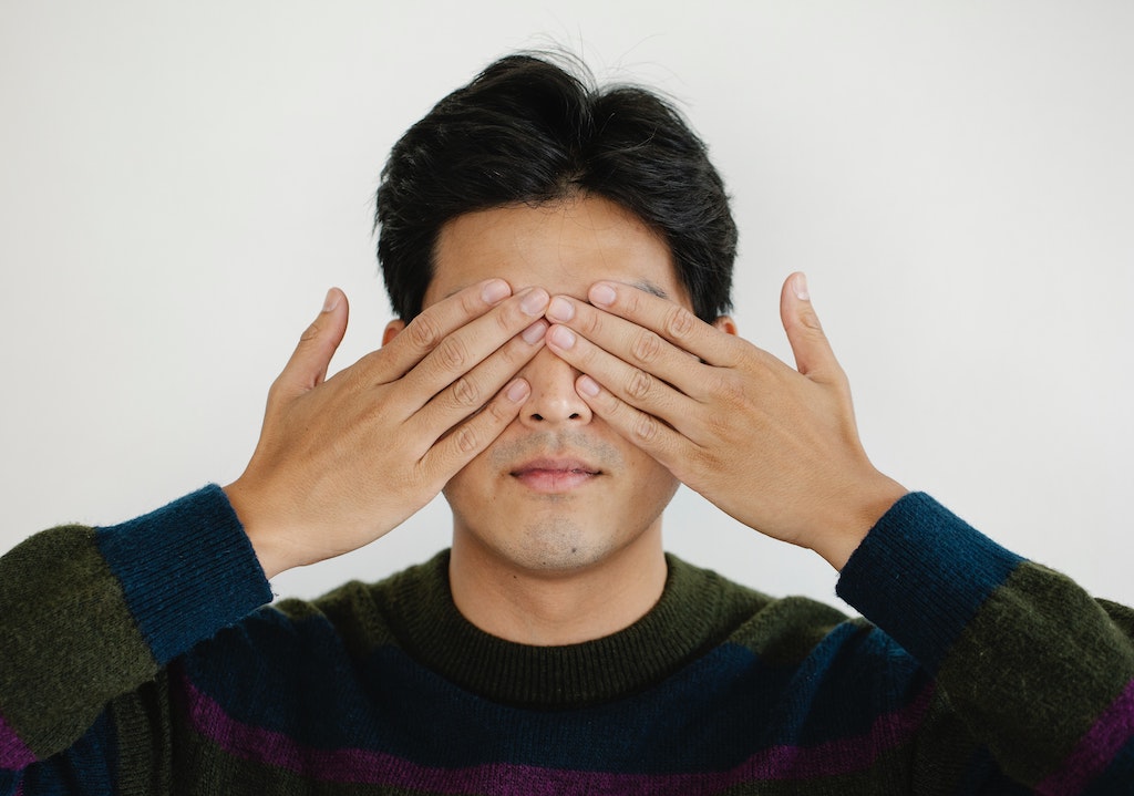 man covering both eyes with hands