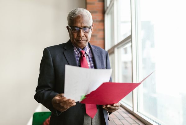 older man standing and looking at papers